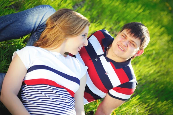 Mladí těhotná pár sedí na zelené trávě na jaře — Stock fotografie