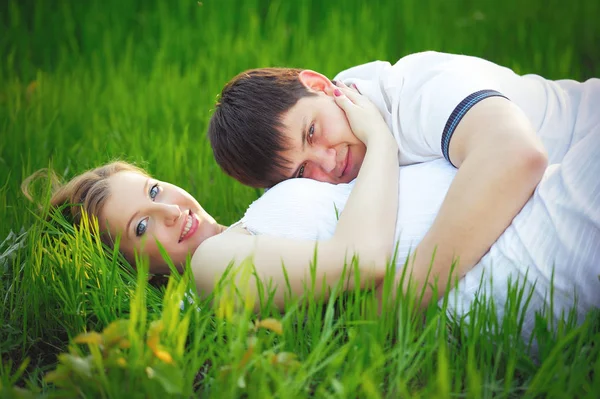 Jovem casal grávida sentado na grama verde na primavera — Fotografia de Stock