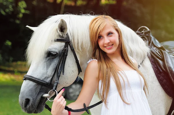 Jovem mulher em um vestido branco em um cavalo branco — Fotografia de Stock