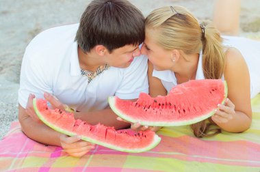 young couple with a watermelon on the shore clipart