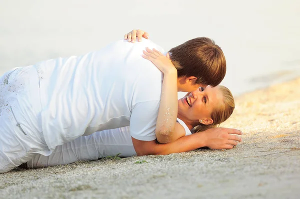 Joven pareja acostada en la playa en ropa blanca —  Fotos de Stock