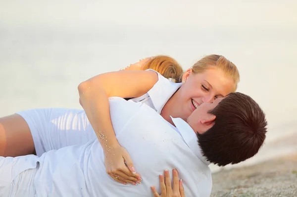 Joven pareja acostada en la playa en ropa blanca — Foto de Stock