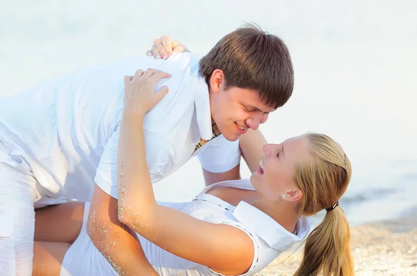 Jovem casal deitado na praia em roupas brancas — Fotografia de Stock