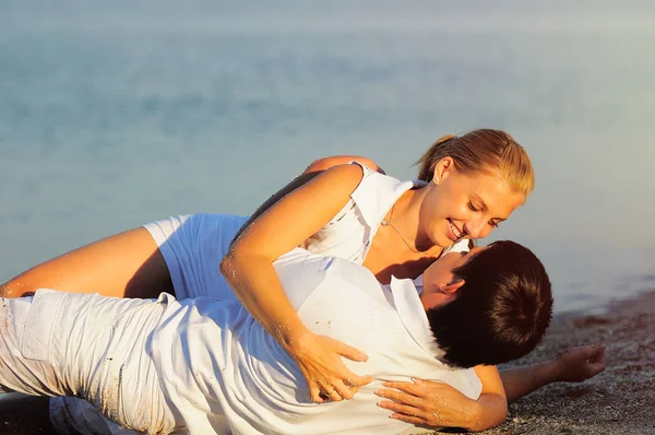 Junges Paar liegt in weißen Kleidern am Strand — Stockfoto