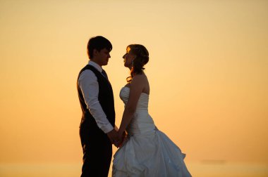 Gelin ve damat sahilde kum üzerinde yürüme