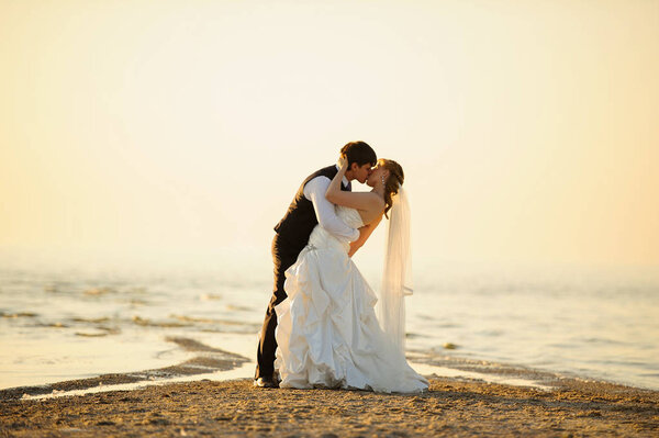 bride and groom walking on the sand on the shore