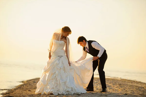 Bride and groom walking on the sand on the shore — Stock Photo, Image