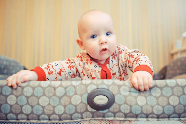 Cute blue-eyes baby peeking out of the crib — стоковое фото