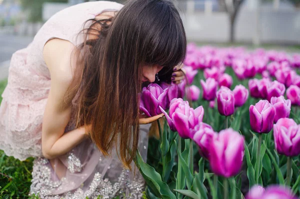 Mulher gentil farejando tulipas — Fotografia de Stock