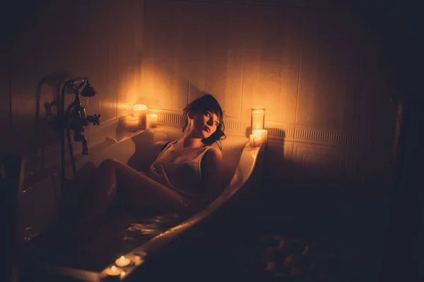 Donna nella vasca da bagno con candele — Foto Stock