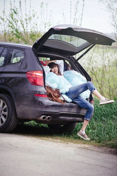 Beautiful woman sitting in the car trunk — Stock Photo, Image