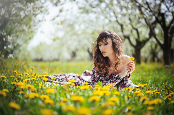 Beautiful woman in long dress lying on the grass in the lush garden