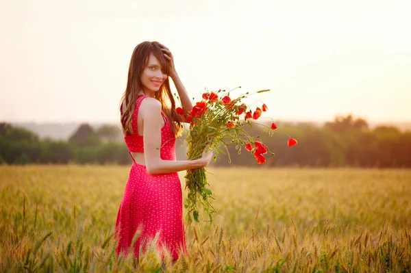 Bela mulher com buquê de papoilas em um campo de trigo — Fotografia de Stock