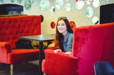 Genç bir Arap kadın bir kafe gözetleme içinde kırmızı bir koltuk üzerinde görünüm