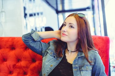 Genç bir Arap kadın bir kafe gözetleme içinde kırmızı bir koltuk üzerinde görünüm