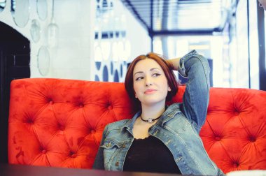 Genç bir Arap kadın bir kafe gözetleme içinde kırmızı bir koltuk üzerinde görünüm