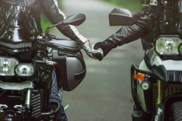 Dois motociclistas estão de mãos dadas enquanto estão sentados em motocicletas — Fotografia de Stock