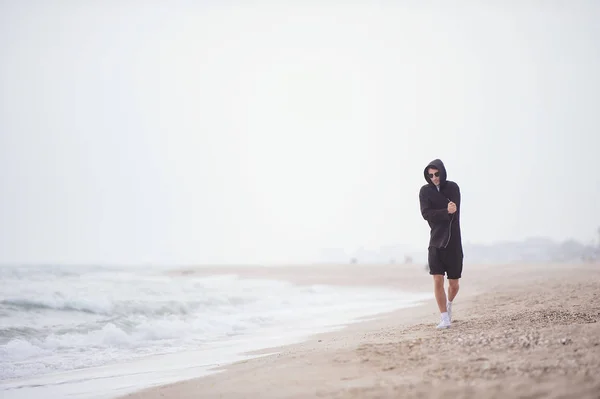 Young fashionable man walking along the beach