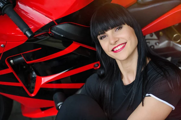Szabadság és a stílus. Egy fiatal nő, egy piros motorkerékpár világos portréja. Motoros lány ül előtt egy motorkerékpár — Stock Fotó