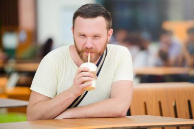 Mutlu adam gülümsüyor, soğuk kahve şehirde bir meşrubat içme sakallı.