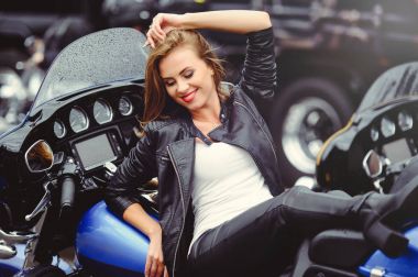 Sokakta parlak bir motosiklet üzerinde rahat güzel kadın gülümsemek güneşli bir günde