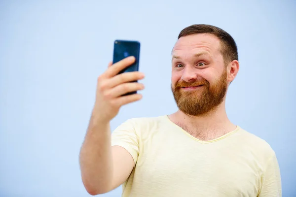 Člověk dělá obličeje v legrační a vtipné telefon ukazuje jazyk, reklamní společnost — Stock fotografie