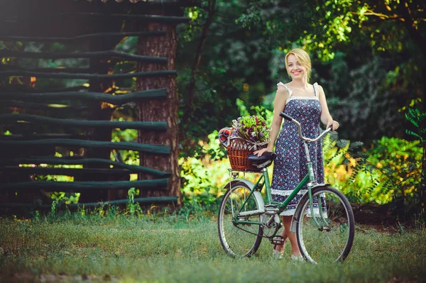 Bisiklet doğa ile güzel genç kadın, sepet çiçek ve arka planda, orman ile rahat neşeli fotoğraf