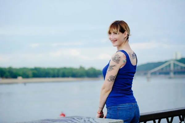 Beautiful happy woman with tattoo beside the river