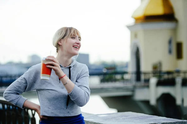 Красивая счастливая молодая женщина пьет кофе в городе, смеется и наслаждается жизнью — стоковое фото