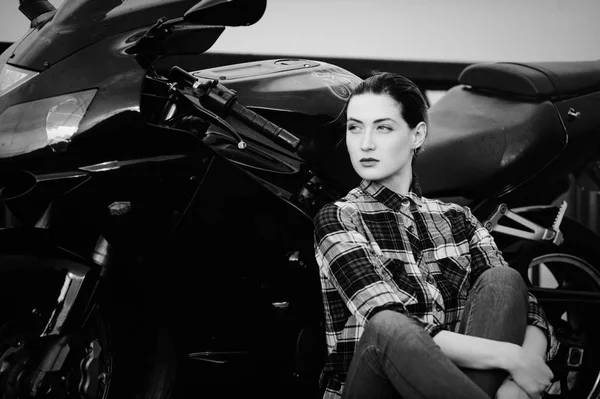 Mujer seria en una camisa sobre un fondo de motocicleta, cabello alisado, blanco y negro — Foto de Stock