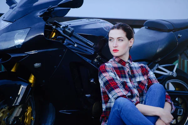 Mujer seria en una camisa sobre un fondo de motocicleta, pelo alisado y lápiz labial rojo — Foto de Stock