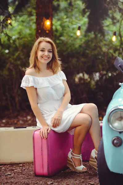 beautiful young woman with suitcases by the car, cheerful blonde, sincere