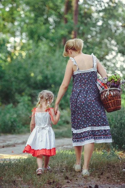 Maman et fille sur la nature sont doux et émotionnels, la vue du dos, feuilles avec un panier dans les mains — Photo