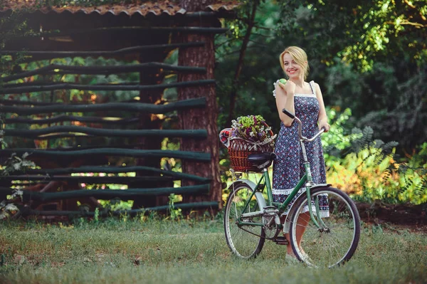 Mujer con una bicicleta en la naturaleza con una manzana en la mano, una cura — Foto de Stock
