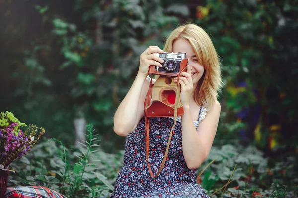 Jovem mulher feliz encontra-se em um piquenique com uma câmera nas mãos, descanso — Fotografia de Stock