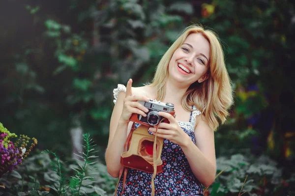 Joven feliz mujer se encuentra en un picnic con una cámara en las manos, descanso — Foto de Stock