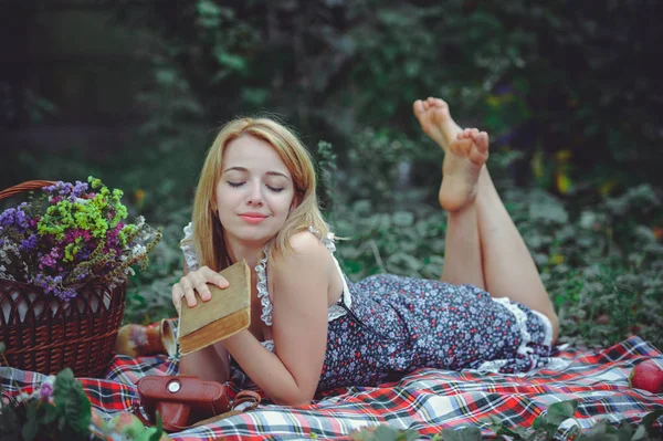 Νεαρή γυναίκα βρίσκεται διαβάζοντας ένα βιβλίο στη φύση, πικνίκ καλόψυχος και απαλή — Φωτογραφία Αρχείου
