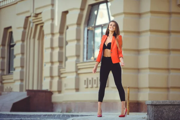 Moda hermosa mujer en chaqueta roja y sujetador negro y pantalones en el fondo de la ciudad — Foto de Stock