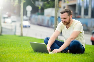 açık havada şehirde çalışan genç adam'ın bahçesinde, bir dizüstü bilgisayar ile