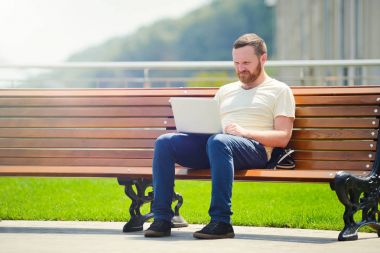 açık havada şehirde çalışan genç adam bankta, dizüstü bilgisayar ile