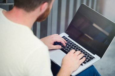 genç adam açık havada şehirde çalışan dizüstü bilgisayar ile