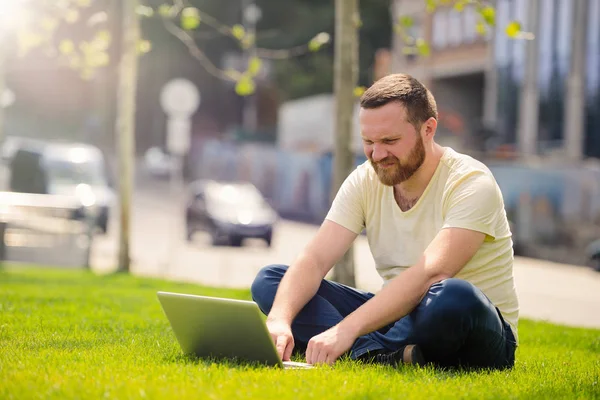 açık havada şehirde çalışan genç adam'ın bahçesinde, bir dizüstü bilgisayar ile