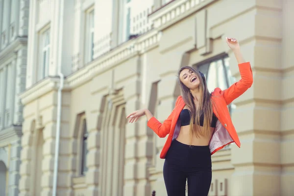 Mujer sonriente de moda escuchando música en auriculares y bailando — Foto de Stock