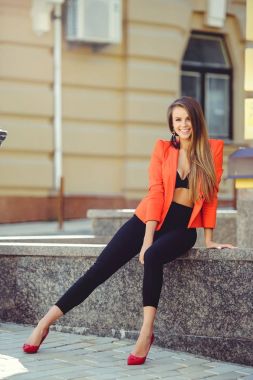 Tatlı bir yüzü bir muamma. Moda kırmızı tarzı ceket ve siyah pantolon ve sutyen yeni ev, yeni bir bina arka plan üzerinde mutlu bir kadın portresi. banner ve reklam için yer