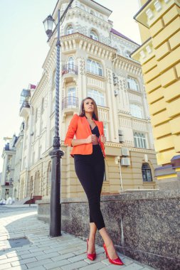 Tatlı bir yüzü bir muamma. Moda kırmızı tarzı ceket ve siyah pantolon ve sutyen yeni ev, yeni bir bina arka plan üzerinde mutlu bir kadın portresi. banner ve reklam için yer