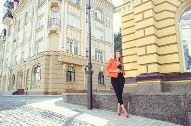 Tatlı bir yüzü bir muamma. Moda kırmızı tarzı ceket ve siyah pantolon ve sutyen yeni ev, yeni bir bina arka plan üzerinde mutlu bir kadın portresi. banner ve reklam için yer