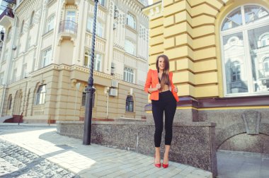 Tatlı bir yüzü bir muamma. Moda kırmızı tarzı ceket ve siyah pantolon ve sutyen yeni ev, yeni bir bina arka plan üzerinde mutlu bir kadın portresi. banner ve reklam için yer