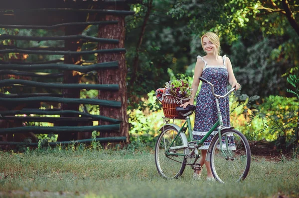 A healthy woman. Beauty Summer model girl with bright colors bicycle forest and basket. style leisure. A beautiful lady with blond hair. Cute face. Cosmetic makeup fashion — Stock Photo, Image