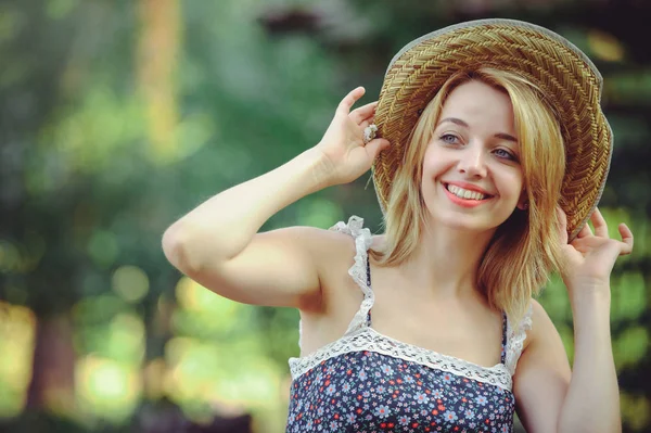 Una mujer sana. Belleza Chica modelo de verano con flores brillantes bosque feliz. estilo de ocio. Una hermosa mujer blanca con sombrero de paja. Una cara bonita con una sonrisa y un misterio. lugar para la bandera y la publicidad — Foto de Stock