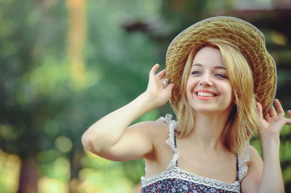 Una mujer sana. Belleza Chica modelo de verano con flores brillantes bosque feliz. estilo de ocio. Una hermosa mujer blanca con sombrero de paja. Una cara bonita con una sonrisa y un misterio. lugar para la bandera y la publicidad — Foto de Stock